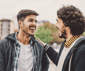 men laughing touching shoulder How to Tell If a Guy is Gay