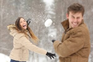 A couple having fun with a snowball fight.