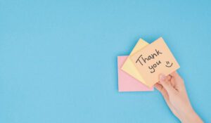 A hand holding a post-it that says: Thank you